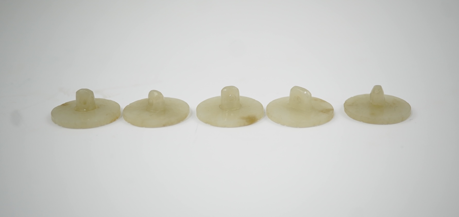 A set of five Chinese pale celadon jade robe buttons, 19th century